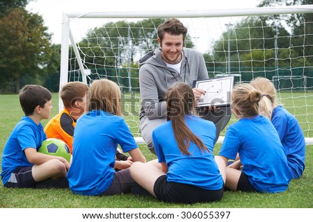 Coach Giving Team Talk To Elementary School Soccer Team