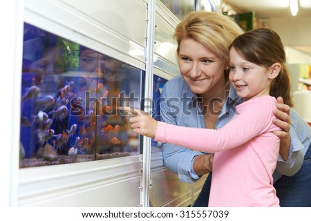 Mother And Daughter Choosing Goldfish In Pet Store