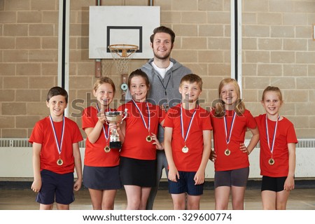 Victorious School Sports Team With Medals And Trophy In Gym