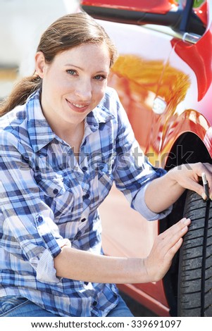 Woman Checking Tread On Car Tyre With Gauge