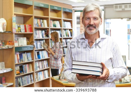Portrait Of Male Bookstore Owner With Customer In Background