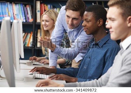 Tutor Working With Group Of Teenage Students Using Computers
