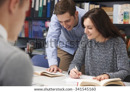 Teacher Helping Female Student In Classroom