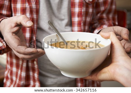 Homeless Man Being Handed Bowl Of Soup By Volunteer