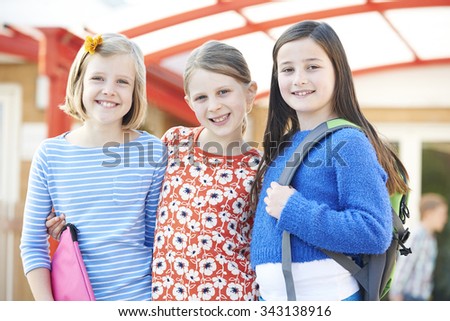 Group Of Girls Standing Outside School With Book Bags