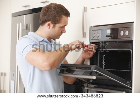 Man Repairing Domestic Oven In Kitchen