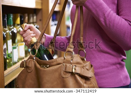 Woman Stealing Bottle Of Wine From Supermarket