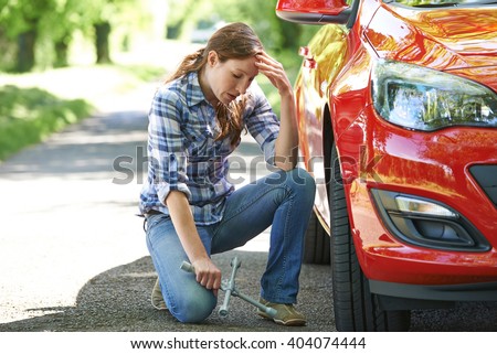 Frustrated Female Driver With Tyre Iron Trying To Change Wheel