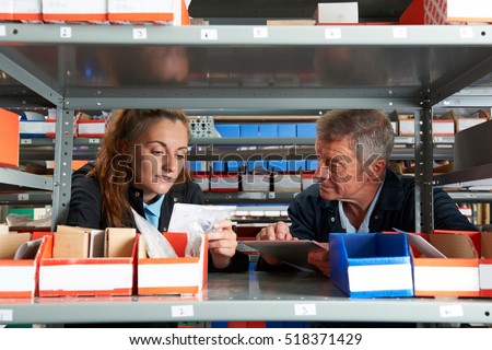 Male Engineer With Female Apprentice Checking Stock Levels