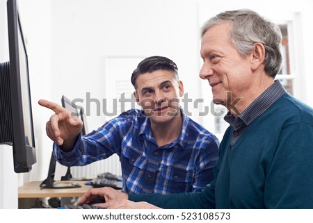 Tutor Helping Mature Man In Computer Class
