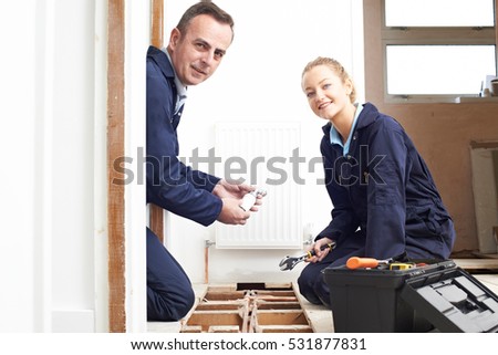 Plumber And Female Apprentice Fitting Central Heating System