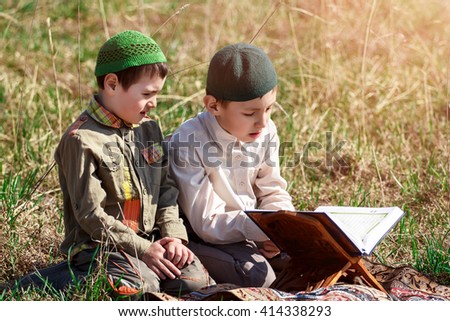 Older brother  is teaching child to read a Quran