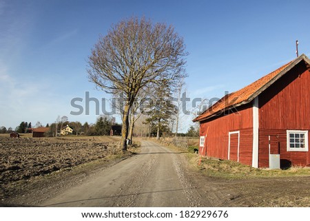 A red barn along a lonely dirt road in the Swedish countryside.