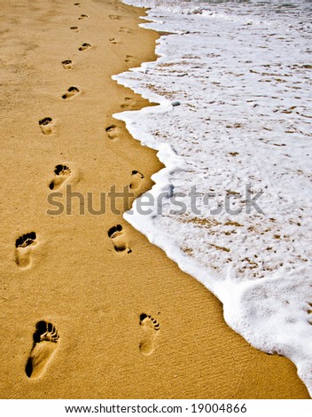 Footsteps in Sand with gritty sand and foamy surf