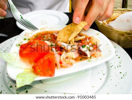 A succulent plate of Mexican ceviche with shrimp and tomato cooked by lime juice.