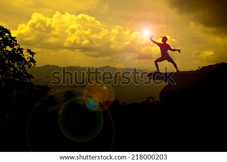 man stand on mountain trying to catch the Sun