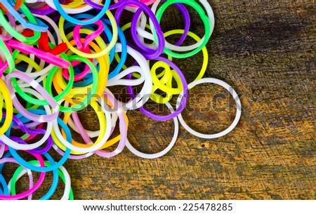 Colorful Rainbow loom bracelet rubber bands fashion on old wood background.