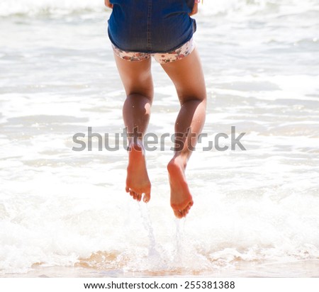 leg of girl jump above the wave on the ocean beach