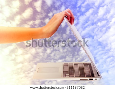 Woman\'s hand open laptop with beautiful cloud and sky background