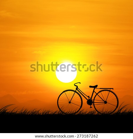 The silhouette of the bike and orange sky at sunset.