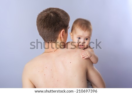 Cute baby looking over father\'s shoulder