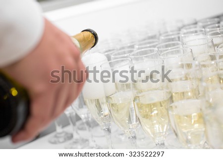 the waiter pours champagne into the glasses
