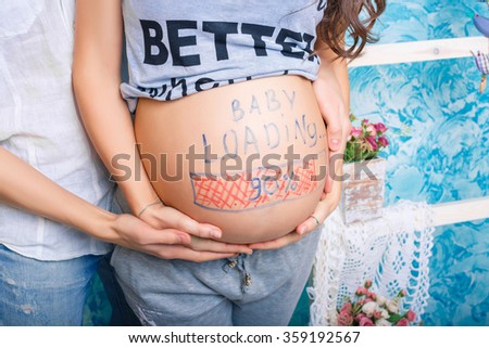 Pregnant woman with loading concept painted on her belly.  word - loading - and figures 90%