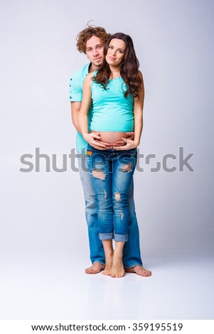beautiful pregnant woman with her husband. future mother and father in blue t-shirt and jeans. happy family