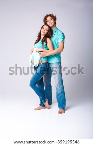 beautiful pregnant woman with her husband holding sliders. future mother and father in blue t-shirt and jeans