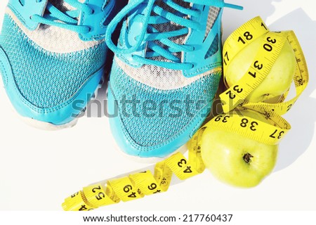 Sport shoes, green apple and a measuring tape. Fitness concept