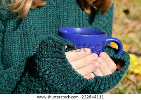 a young ,beautiful girl in the green sweater,holding a hot Cup of coffee,autumn concept,autumn,autumn themes,heat,blue Cup
