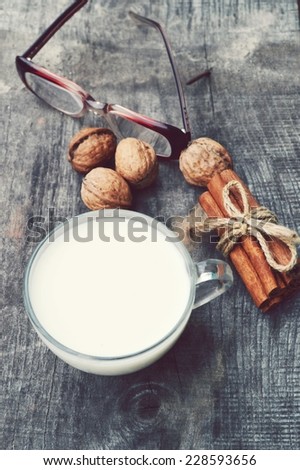 cup of hot milk with cinnamon , Spices and hazelnuts, walnuts, closeup on wooden background