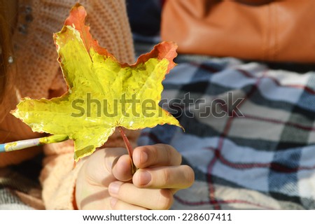 a young,beautiful girl paints maple leaf ,drawing,autumn concept
