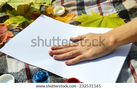 a young,beautiful girl draws a hand print on the paper paints