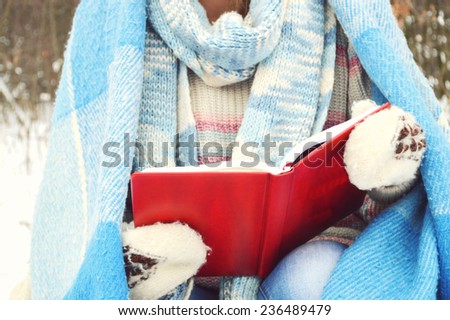 girl wrapped a blanket reading a book. winter concept