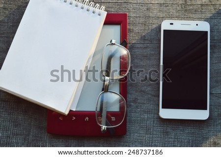 white smartphone and e-book on wooden background.Notepad,diary,record