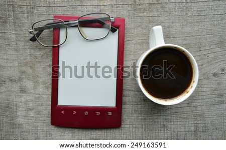 red e-book,Notepad,read ing glasses,hot Cup of coffee on wooden background