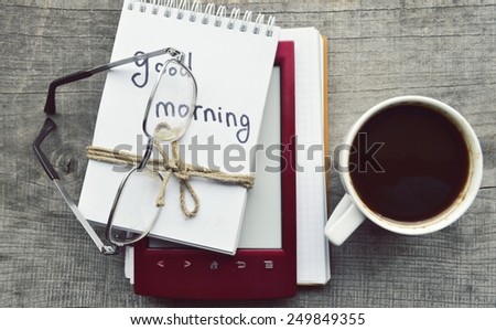 e-book.Notepad,reading glasses,hot Cup of coffee on wooden background.