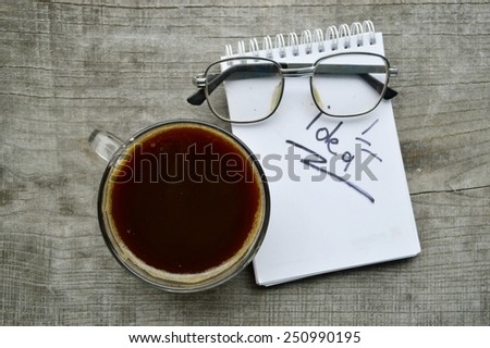 ,Notepad,reading glasses,hot Cup of coffee on wooden background