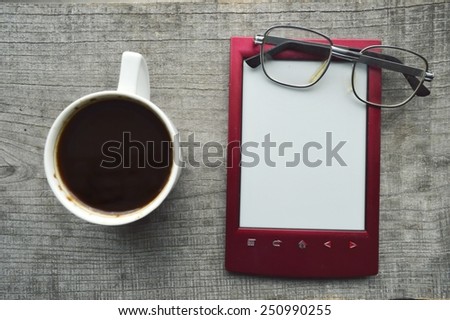 red e-book,Notepad,reading glasses,hot Cup of coffee on wooden background
