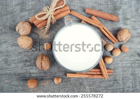 cup of hot milk with cinnamon , Spices and hazelnuts, walnuts, closeup on wooden background