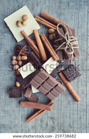 bar of chocolate, coffee beans, hazelnuts, walnuts, cinnamon, coriander, spices .chocolate bar, candy bars,  different chocolate sweets on a wooden background.big choice of various sweets