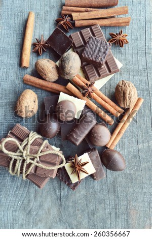 bar of chocolate, coffee beans, hazelnuts, walnuts, cinnamon, coriander, spices .chocolate bar, candy bars,  different chocolate sweets on a wooden background.big
