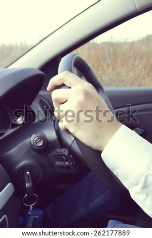Male driver hands holding steering wheel