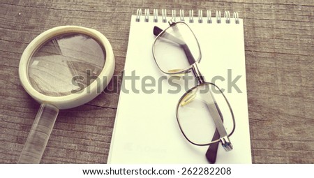 vintage reading glasses, magnifying loupe, note pad, diary, diary on wooden background