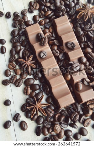 bar of dark chocolate, milk chocolate bar, coffee beans, star anise, cinnamon sticks, seasonings, spices, close-up on a white wooden background