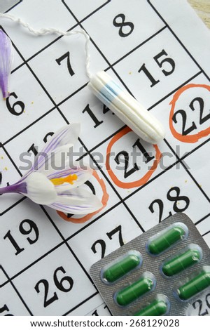 Woman hygiene protection, close-up.menstruation calendar with cotton tampons,orange Gerber,Sanitary pads.Spring flowers, femininity, tenderness, birth control pills