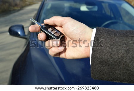 a hand holding a car\'s remote control pointing to the door.a man opens a machine