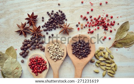 red pepper peas,black pepper peas,white pepper corns,a Bay leaf,cardamom on wooden background