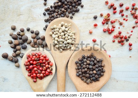 red pepper peas,black pepper peas,white pepper corns,a Bay leaf,cardamom on wooden background